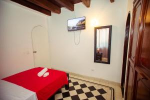 Habitación con cama roja y TV en la pared. en Casa Hotel Marbella Beach, en Cartagena de Indias