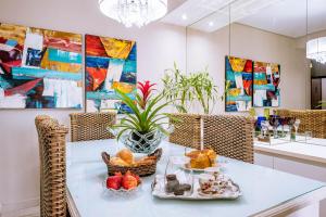 una mesa con comida en una habitación con pinturas en VARANDA GOURMET c churrasqueira-3 quartos- Wi-fi, en Bertioga