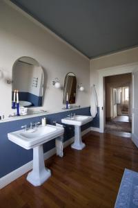 a bathroom with two sinks and two mirrors at Castello di Coazzolo in Neive