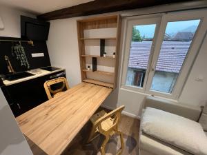 uma pequena cozinha com uma mesa de madeira e uma janela em LE COQUET hyper centre climatisé em Salins-les-Bains