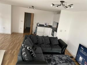 a living room with a black couch and a kitchen at King Dems Home in Dagenham