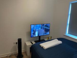 a bedroom with a flat screen tv on a bed at King Dems Home in Dagenham