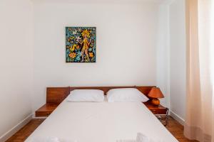 - un lit dans une chambre avec une photo sur le mur dans l'établissement Maison des Demoiselles - Welkeys, à Puilboreau