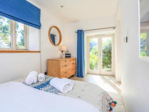 a bedroom with a bed and a dresser and windows at Linham Barn in Kingsbridge