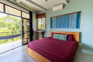 a bedroom with a bed with purple sheets and a window at Casa Paraíso - 3rd Floor in San Juan del Sur