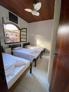 a room with three beds and a window and a door at Giprita Wellness Hotel Ubatuba in Ubatuba