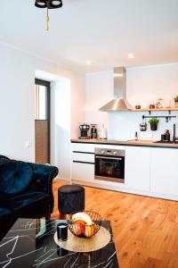 a living room with a black couch and a kitchen at Albatross Dimants - apartamenti Rīgas jūras līča krastā in Ķesterciems