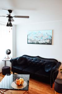 a black leather couch in a living room with a table at Albatross Dimants - apartamenti Rīgas jūras līča krastā in Ķesterciems