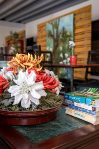 a table with a bowl of flowers and books on it at Casa María Aeropuerto B&B in Alajuela