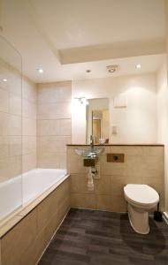 a bathroom with a tub and a toilet and a sink at 62-66 Farringdon Apartments by condokeeper in London