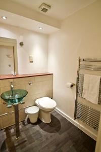 a bathroom with a toilet and a glass sink at 62-66 Farringdon Apartments by condokeeper in London