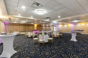 um salão de banquetes com mesas e cadeiras brancas e iluminação roxa em Wyndham Garden Manassas em Manassas