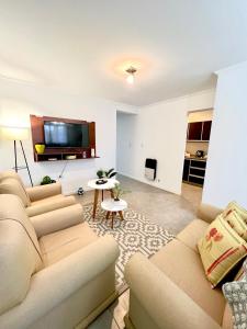 sala de estar con 2 sofás y TV de pantalla plana en Lumiere Apartments - Luminoso Departamento en Complejo Residencial en Mendoza