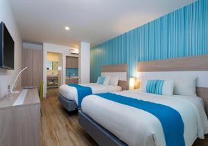 una camera d'albergo con due letti e una televisione di Aqualina Inn a San Andrés