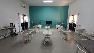 a room with tables and chairs and a blue wall at Hotel Sun City in Itápolis