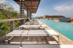 a row of lounge chairs next to a swimming pool at Bello Departamento Veleros frente al mar in Acapulco