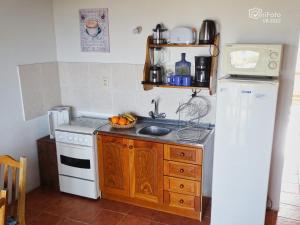cocina con nevera blanca y fregadero en Complejo Dunas del Diablo en Punta Del Diablo