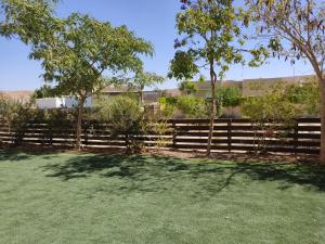 a fence in a yard with trees and grass at רוגע במדבר מרחב עם in Merhav Am
