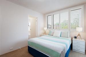 ein weißes Schlafzimmer mit einem Bett und einem Fenster in der Unterkunft Columbia, 3 12 Columbia Close - large unit with fantastic water views and wifi in Nelson Bay
