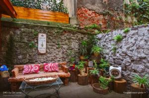 a bench with pink pillows sitting next to a stone wall at Hidden Garden Suites in Istanbul