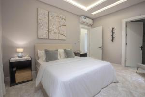 a white bedroom with a large white bed and a table at Spacious and Modern Apartment for Rent in Ergah, Riyadh in Riyadh