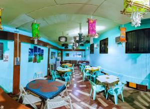 un restaurante con mesas, sillas y luces coloridas en Apo Pension House, en Corón