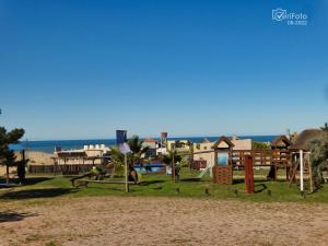 un parque infantil en la playa con el océano en el fondo en Complejo Dunas del Diablo en Punta Del Diablo