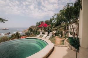 a swimming pool with chairs and a view of the ocean at HEVEN Residence in Zipolite