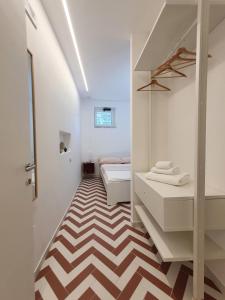 biały pokój z 2 łóżkami i podłogą w paskach w obiekcie La Casa di Mina w mieście Monte di Procida