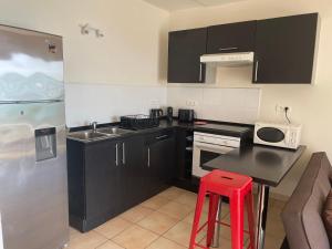 a kitchen with black cabinets and a red stool at Studio Moana in Bora Bora