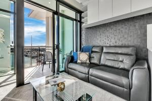 uma sala de estar com um sofá de couro e uma mesa de vidro em Penthouse Premier em Auckland