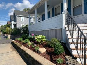 a house with a staircase and flowers in a yard at Bright 2 Br, Pets Welcome, Steps to Lake, Restaurants and Train in Wakefield
