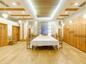 网走市Tabist Abashiri Central Hotel的一间大型用餐室,配有白色的桌子和椅子