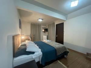 a bedroom with a large bed with blue sheets and pillows at Chalé do Recanto in Lumiar