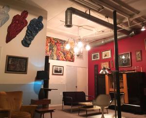 a room with red walls with chairs and artwork at SPACE CASTLE: a 1950s Gas Station transformed into an Art Themed Wonderland in Truth or Consequences