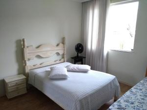 1 dormitorio con cama blanca y ventana en Casa verde, en Belo Horizonte