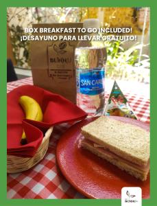 un panino su un piatto rosso su un tavolo con scatola e banane di Eco Bunnu Inn a Cuzco