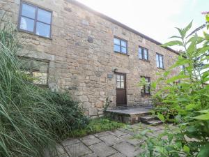 an old brick building with a door and a bench at Mill House Barn in Gulval