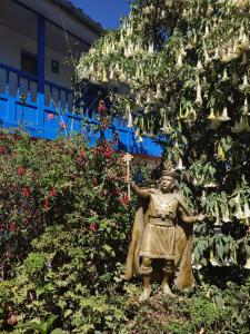 una estatua de una mujer parada frente a un árbol en Las Portadas, en Ollantaytambo