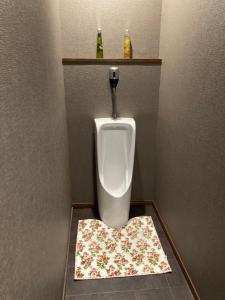 a bathroom with a urinal with a flower rug on the floor at Bamboo-Hill Sasaoka in Nozawa Onsen