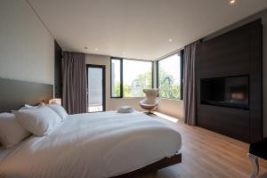 a bedroom with a large white bed and a flat screen tv at Aozora in Kutchan