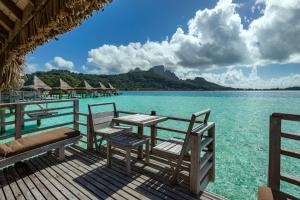 een tafel en stoelen op een steiger in het water bij InterContinental Bora Bora Le Moana Resort, an IHG Hotel in Bora Bora