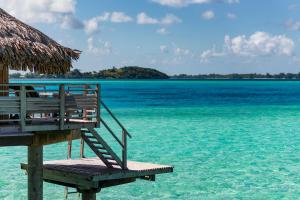 a wooden bench sitting on top of a sandy beach at InterContinental Bora Bora Le Moana Resort, an IHG Hotel in Bora Bora
