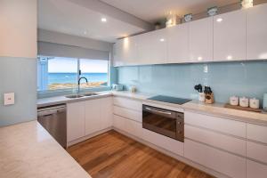 cocina con armarios blancos y vistas al océano en Busselton Beach House, en Busselton