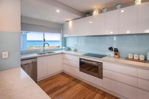 a kitchen with white cabinets and a view of the ocean at Busselton Beach House in Busselton
