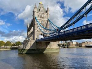 a suspension bridge over the water in front of a city at APlaceToStay Central London Apartment, Zone 1 in London
