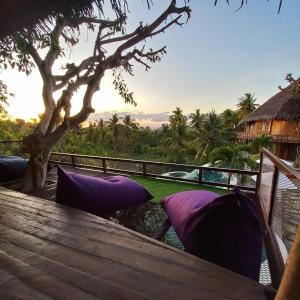 a wooden deck with purple pillows and a view of the ocean at Gading Tree House in Nusa Penida