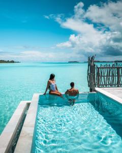 un hombre y una mujer sentados en una piscina en el agua en InterContinental Bora Bora & Thalasso Spa, an IHG Hotel en Bora Bora