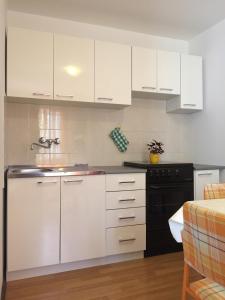 una cocina con armarios blancos y un aparato negro en Seaside holiday house Vis - 8902 en Vis