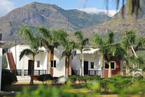 a house with palm trees in front of a mountain at Green Garden Resort in Kuttālam